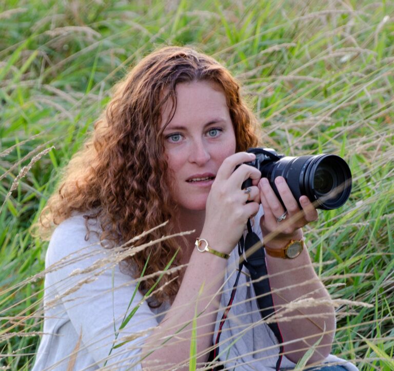 Erin Burrell holding camera in the middle of tall grass