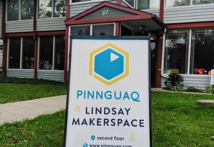 A Pinnguac sign on a lawn in front of a large building